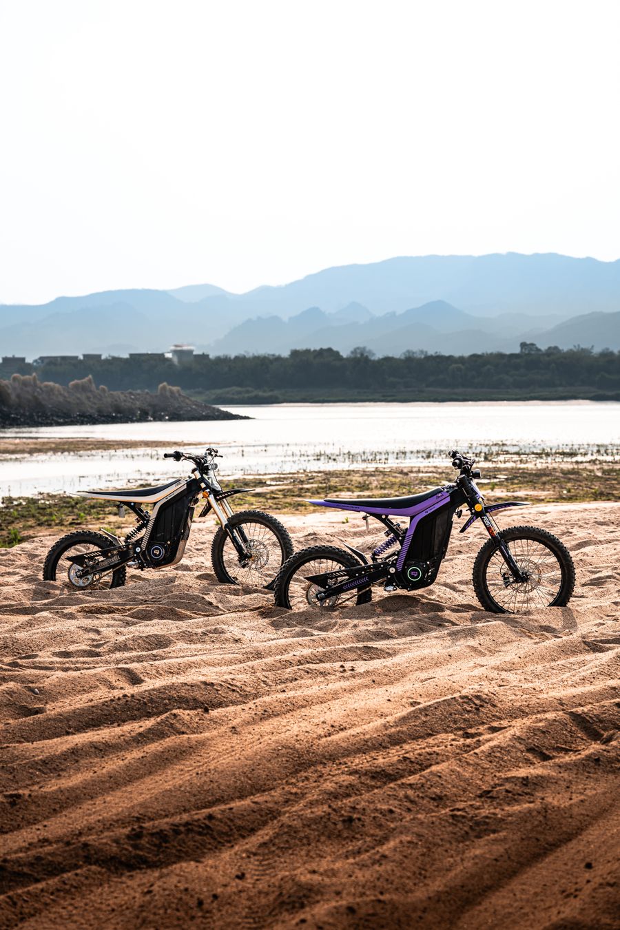 Two Sur-Ron electric dirt bikes on the sand