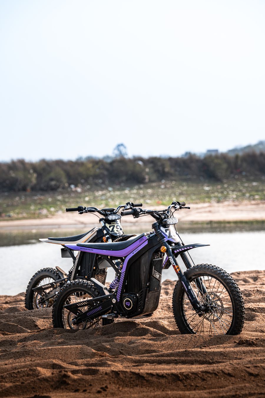 Two custom Sur-Ron electric dirt bikes on the sand