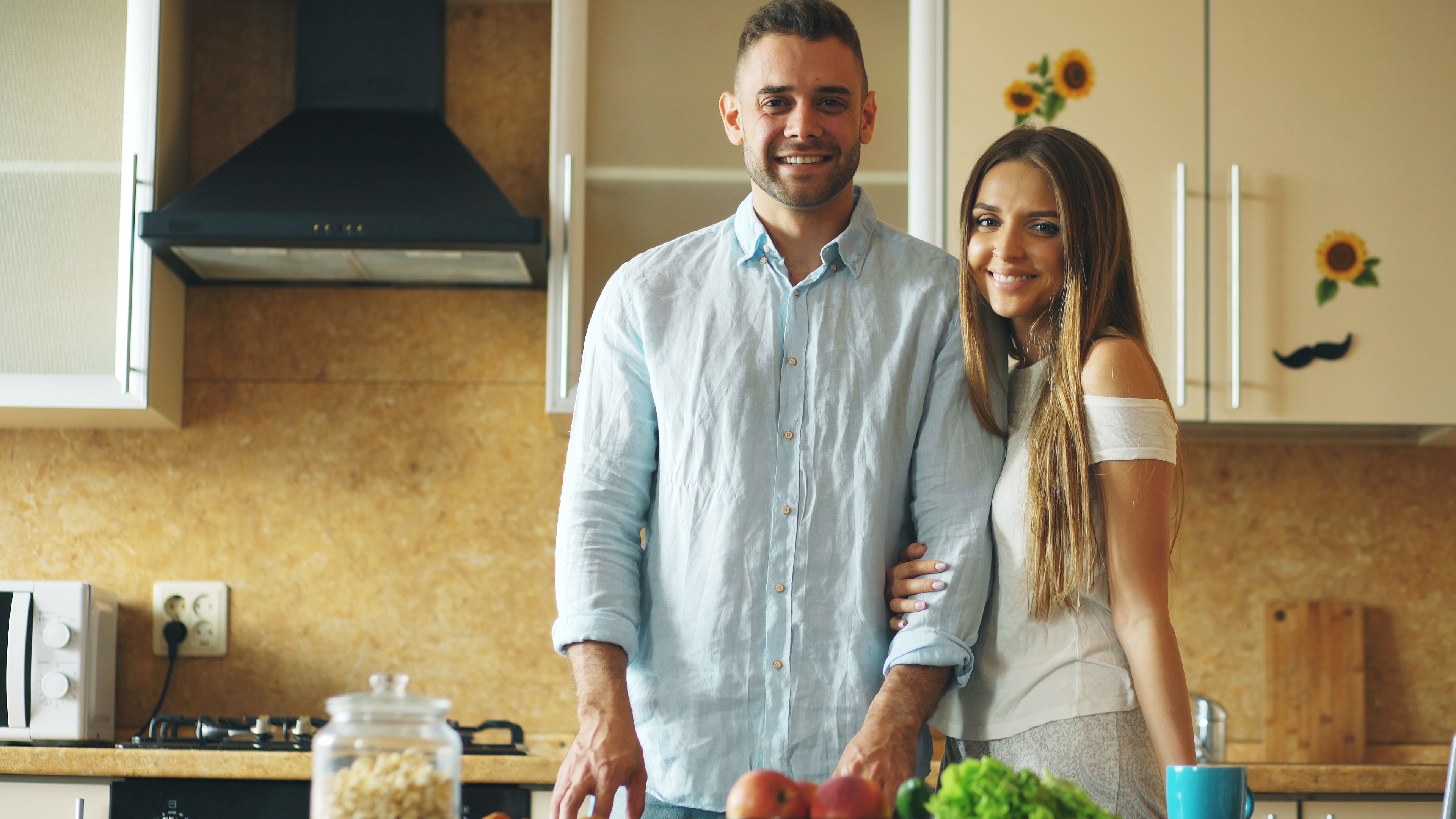 Happy couple standing in a cozy kitchen with healthy vegetables. Perfect for lifestyle and home themes.