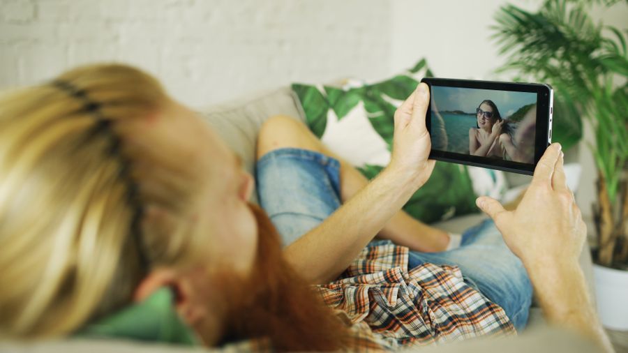 A person reclining on a couch watching a video on a tablet at home