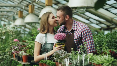 Free Loving couple sharing a tender moment surrounded by plants in a greenhouse. Stock Photo