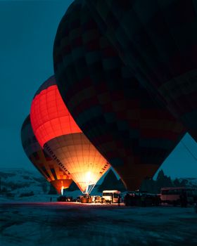 Glowing hot air balloons preparing for a flight at night in Cappadocia, Turkey.