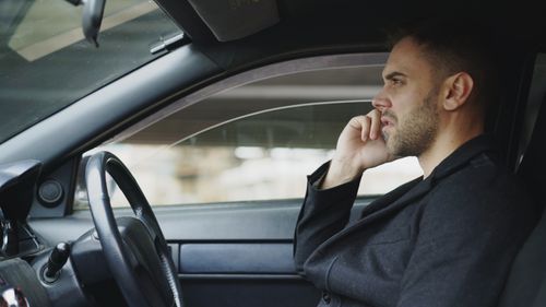 Free Focused man talking on smartphone in a car during the day, highlighting modern communication. Stock Photo