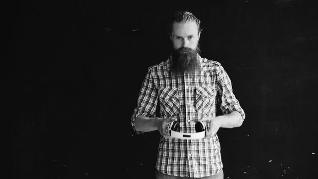 Bearded man in plaid shirt holding a virtual reality headset, black and white portrait.