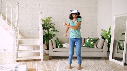 Free A woman in a casual setting enjoying virtual reality with a headset. Stock Photo