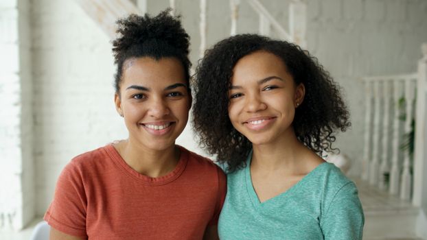 A warm indoor portrait of a smiling mother and daughter posing together, radiating happiness.