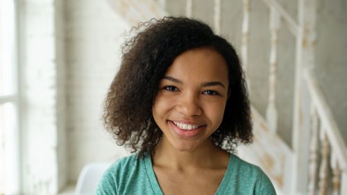 Free A cheerful young woman smiles brightly in an indoor setting with rustic decor. Stock Photo