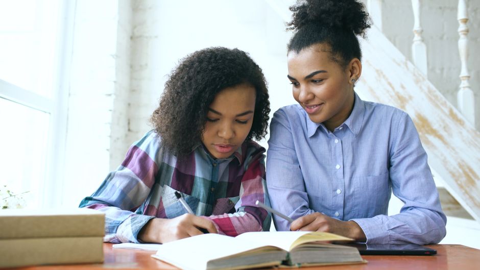 Teen studying with an adult at a home table, focusing on learning and education. Teen studying with an adult at a home table, focusing on learning and education.