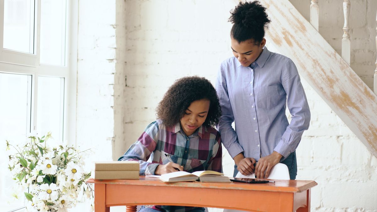 Mother helping daughter with homework at home in warm daylight