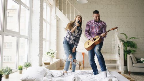 Free Happy couple enjoying music with microphone and guitar indoors. Stock Photo