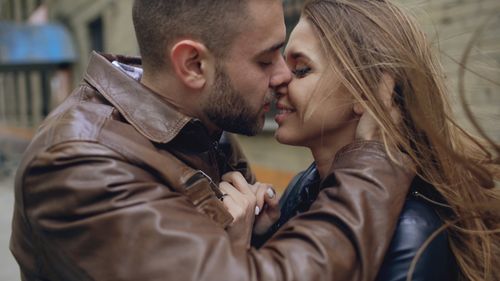 Free A romantic couple in a close embrace outdoors, wind in their hair, expressing love and affection. Stock Photo