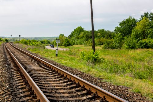 Free Curving railway tracks surrounded by green fields and trees under a clear sky. Stock Photo