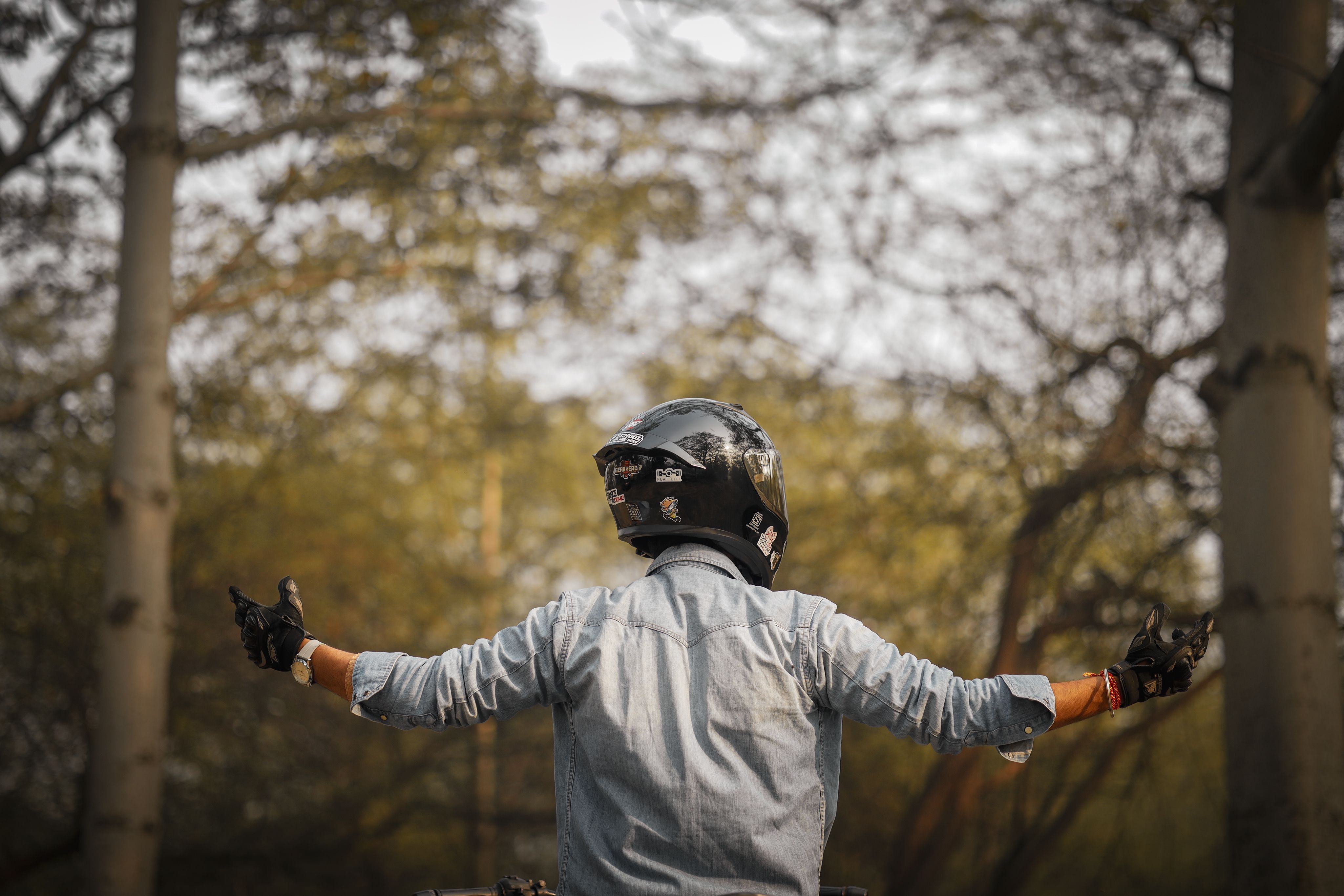 A motorcyclist wearing a helmet and gloves enjoys the tranquility of a forest environment.