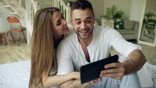 Free Smiling couple taking a cheerful selfie together indoors on a cozy morning. Stock Photo
