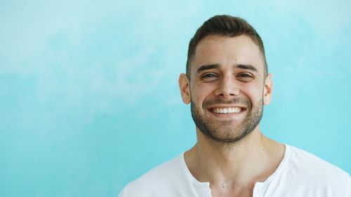 Free Portrait of a smiling man in a white shirt with a blue background, showcasing positivity. Stock Photo
