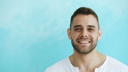 Free Portrait of a smiling man in a white shirt against a light blue background. Stock Photo
