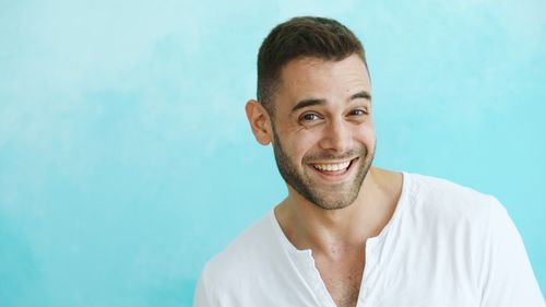 Free Portrait of a cheerful man wearing a white shirt against a blue background. Stock Photo