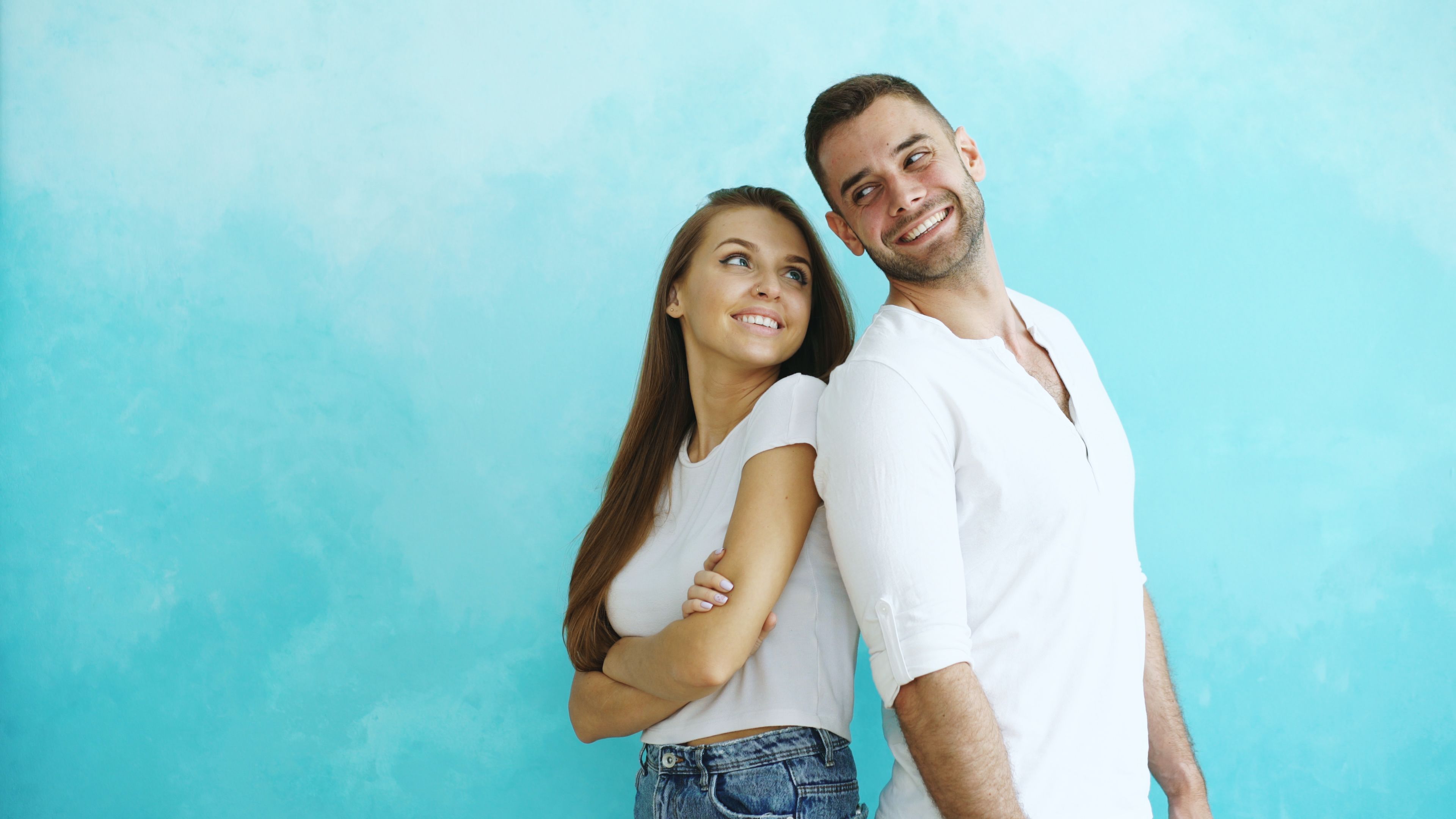 A cheerful couple poses with smiles in a bright setting, exuding joy and positivity.