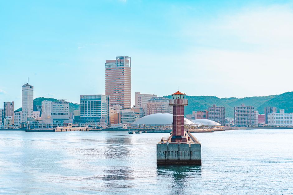 Explore the vibrant skyline of Takamatsu, Japan with a picturesque lighthouse in the foreground.