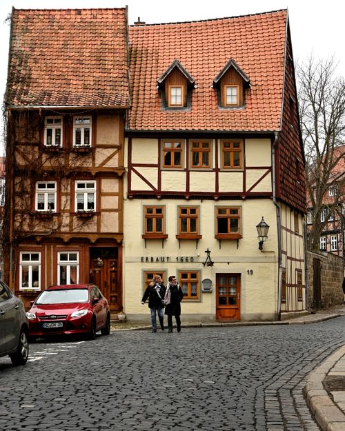 Free Scenic view of historic half-timbered houses in Quedlinburg, Germany during winter with people on cobblestone street. Stock Photo