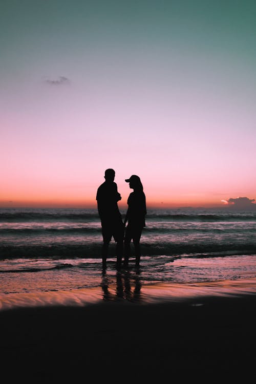Schattenbild Des Paares, Das Am Strand Während Des Sonnenuntergangs Steht