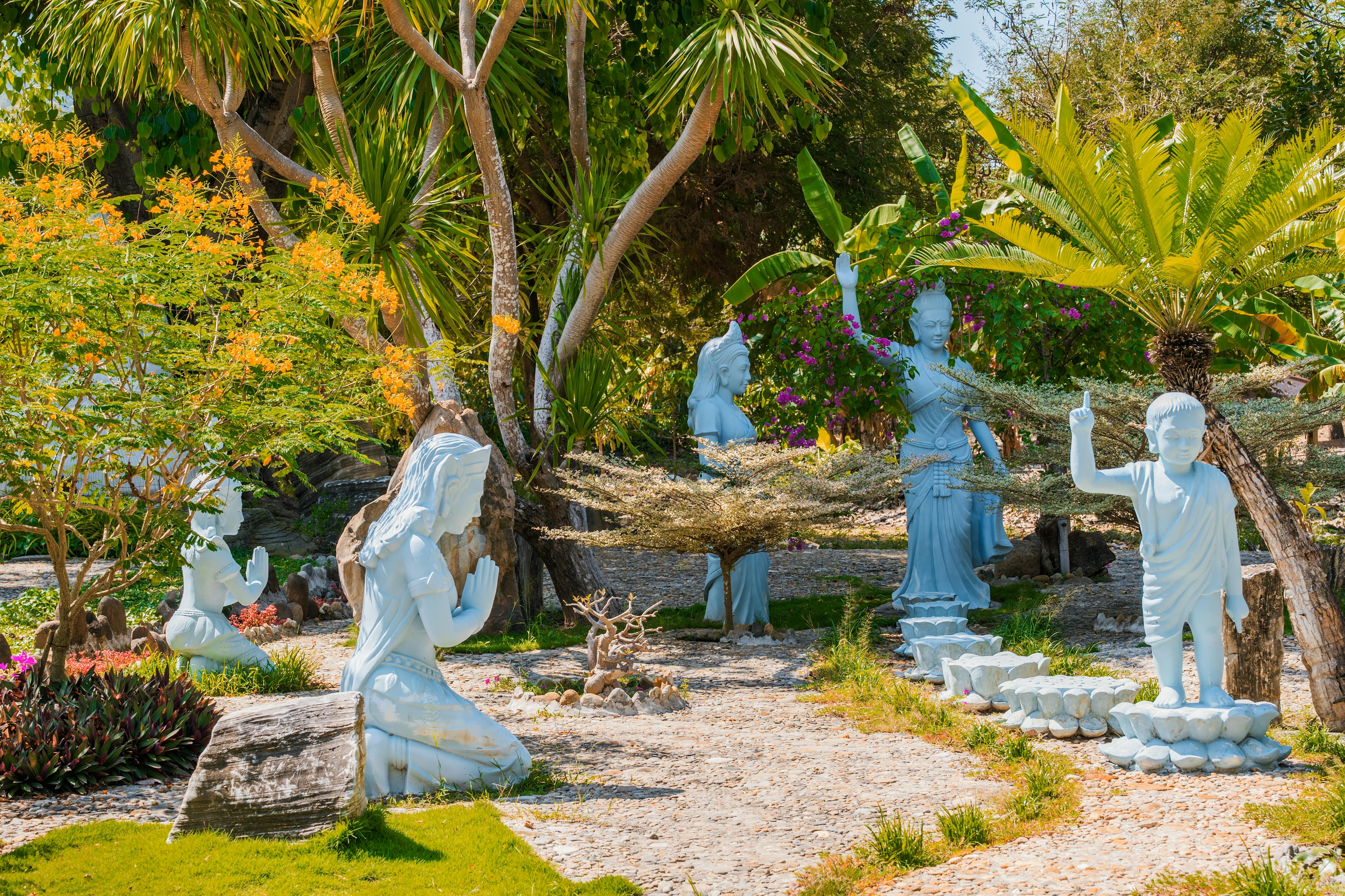 Outdoor sculpture garden at Haw Par Villa Singapore with painted statues depicting Chinese folklore scenes along a tree-lined path