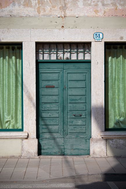 Charming green door framed by stone in Palmanova, Italy's historic town.