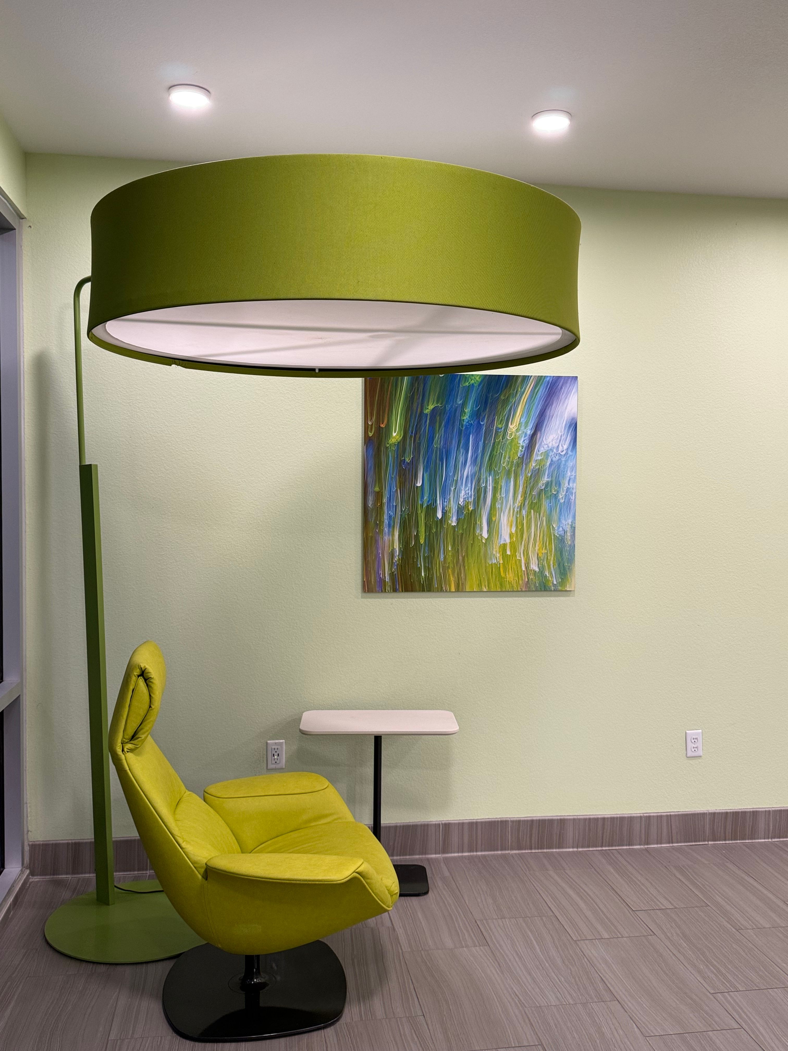 A sleek modern interior featuring a green lamp and chair against a soft pastel backdrop.