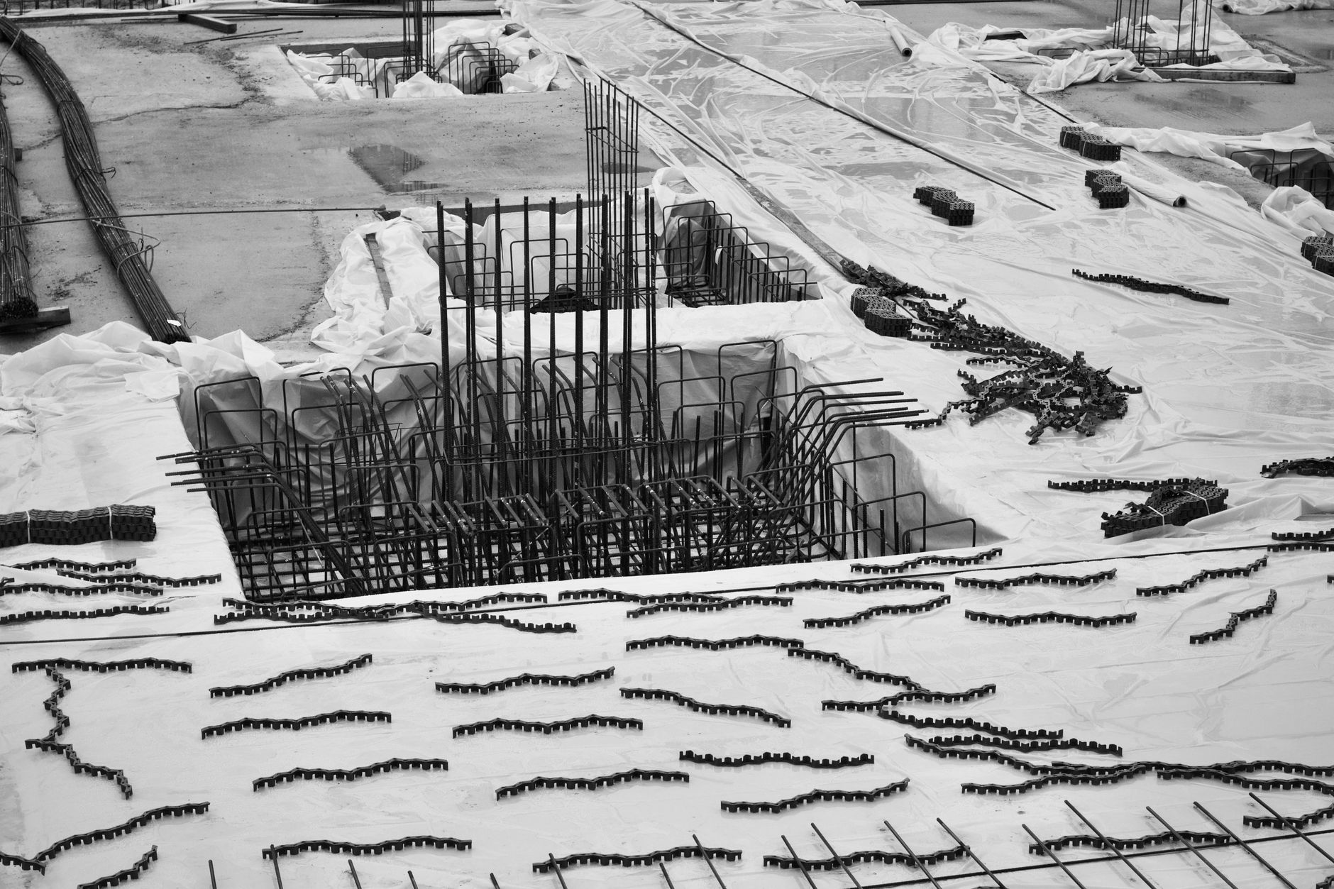 Black and white aerial shot of a construction site with rebar framework, showcasing industrial building materials and layout.