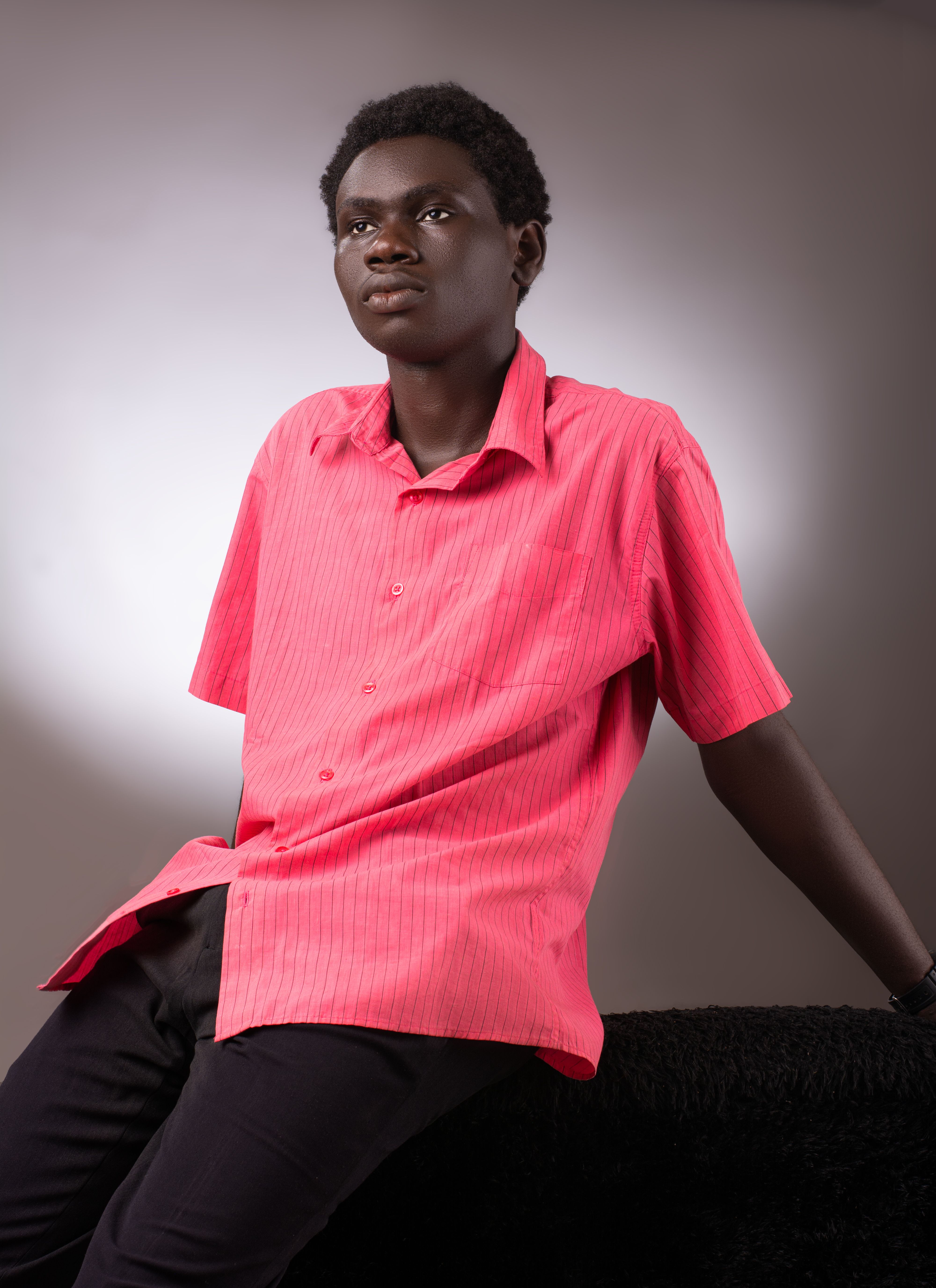 Portrait of a young man sitting and posing in a bright red shirt.