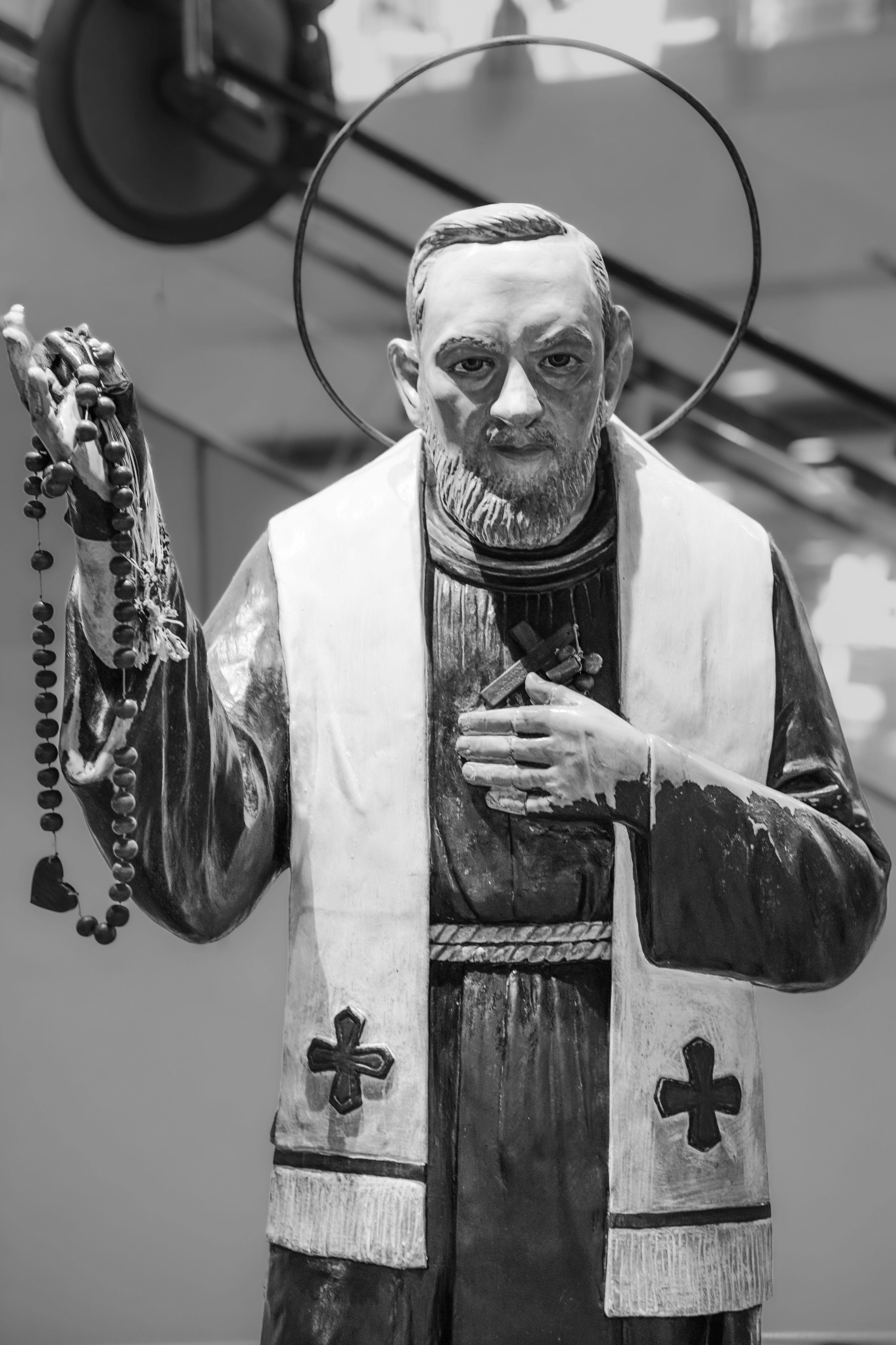 Monochrome statue of a saint holding rosary beads, symbolizing faith and spirituality.