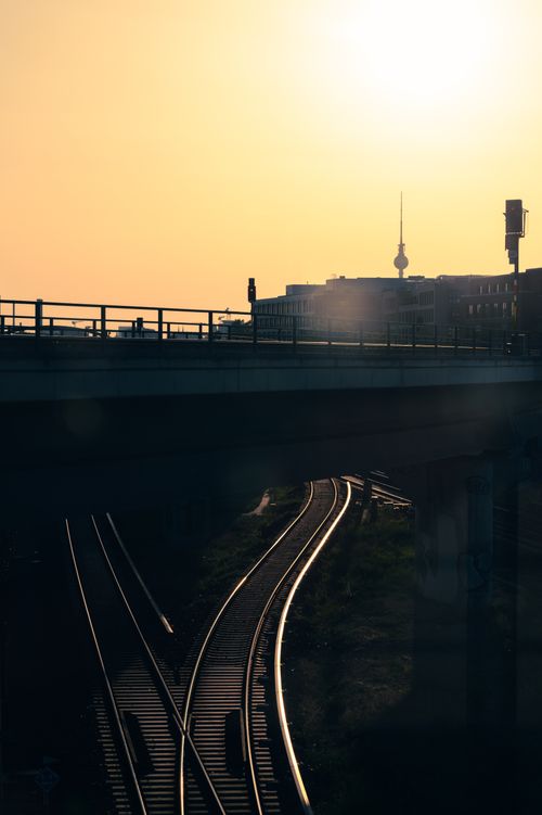 Free Silhouetted view of Berlin's railway tracks with the TV tower at sunset, featuring urban architecture. Stock Photo