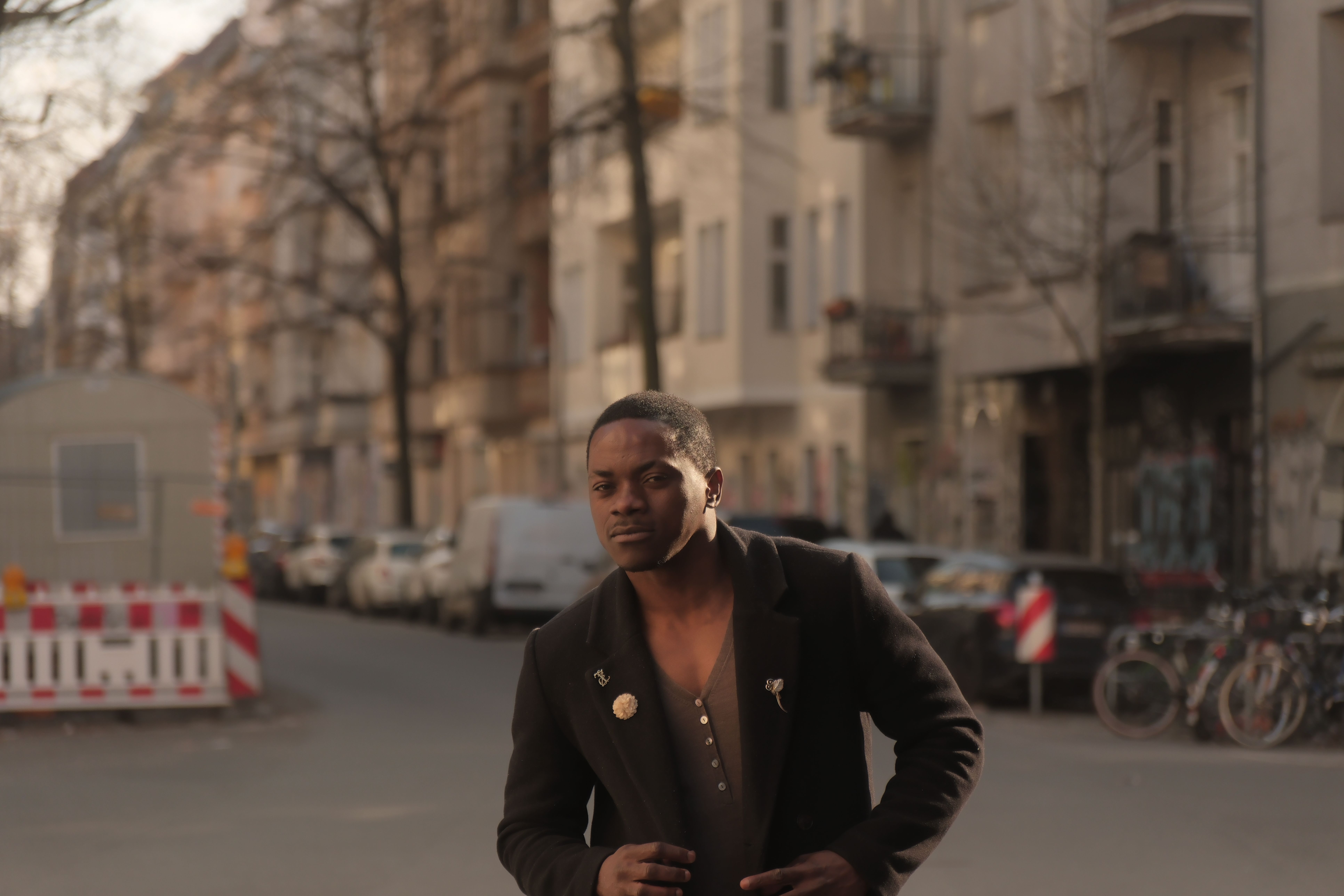 A man in a black coat strolling down a Berlin street, showcasing urban life and fashion.