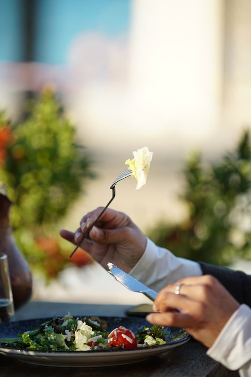 Free A person enjoying a fresh salad at an outdoor dining setting, captured mid-bite with a fork. Stock Photo