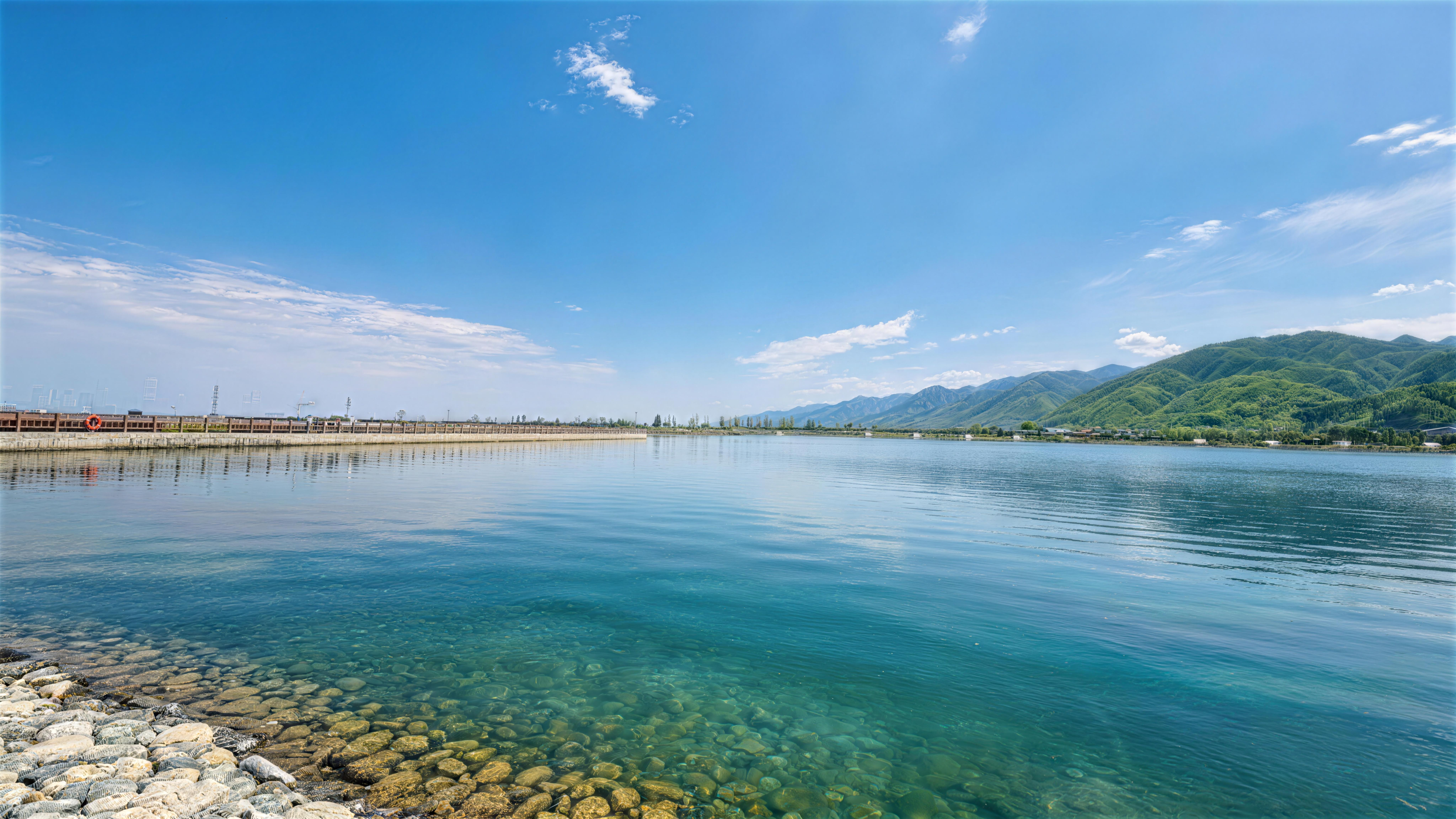 Peaceful lake scene with mountains and clear blue sky.