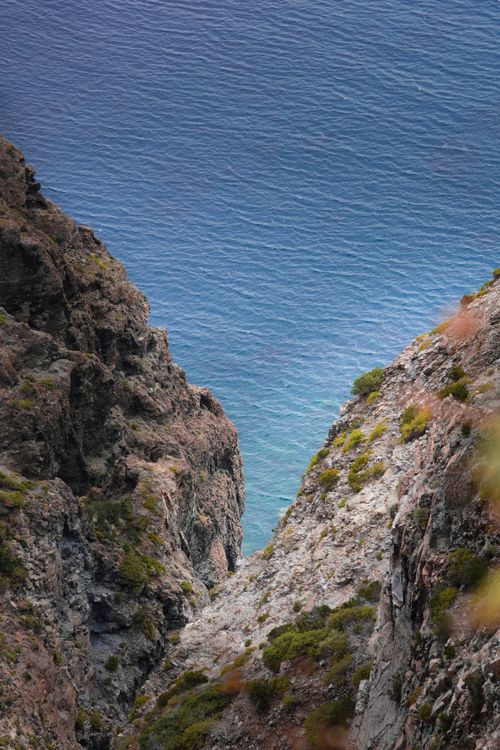 Free Panoramic view of rugged cliffs meeting azure sea in Pantelleria, Sicily, capturing natural beauty. Stock Photo