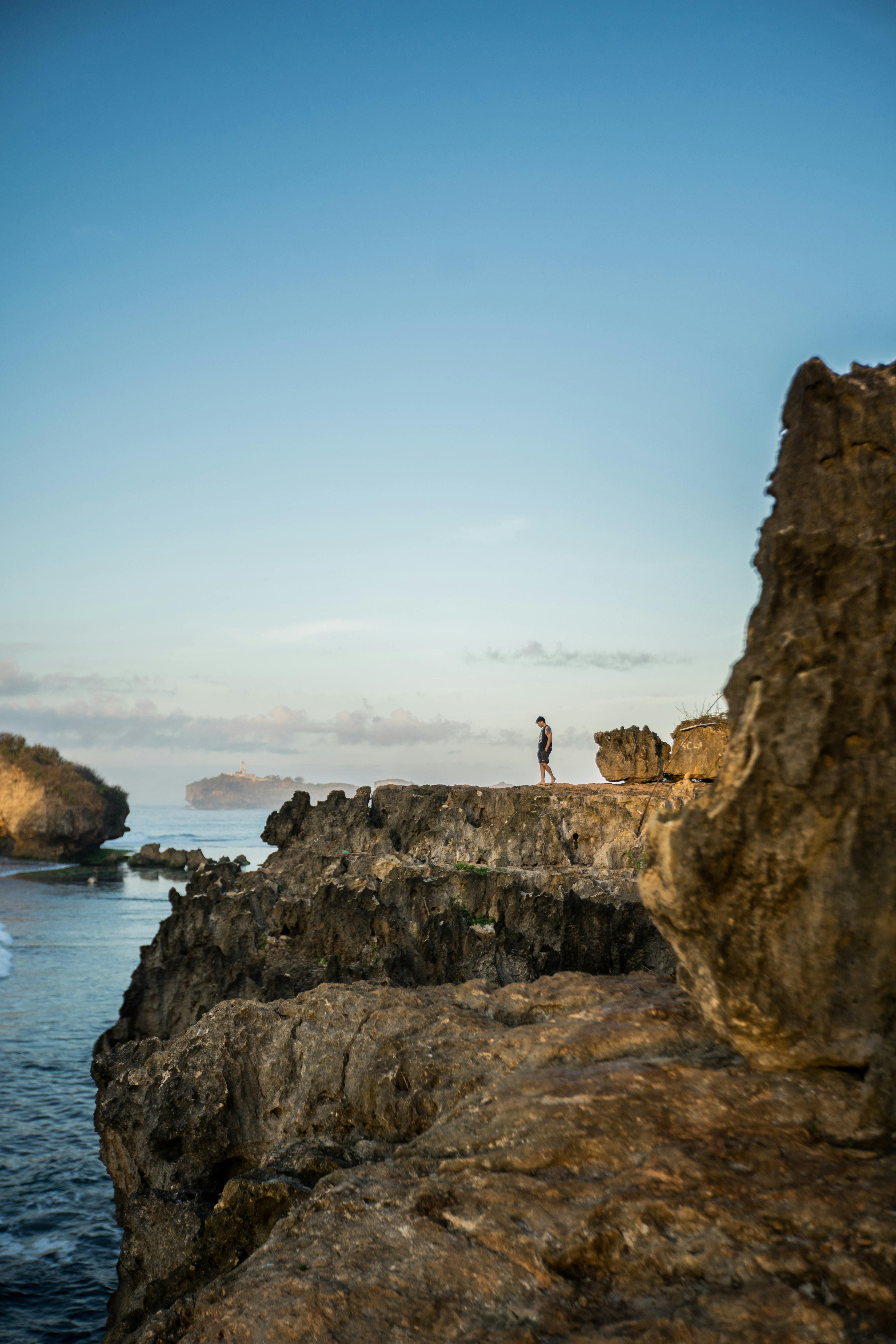 person standing on rock formation near body of water