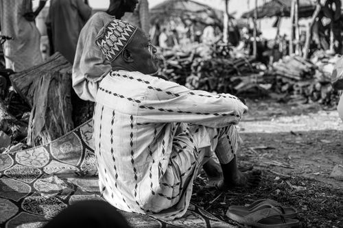 Free Senior man sitting outdoors in a traditional African market, contemplating. Stock Photo