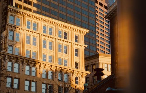 Free Golden sunlight illuminates historic and modern architecture in a cityscape at sunset. Stock Photo