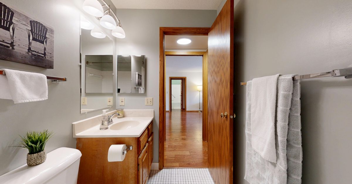 Elegant bathroom with wood cabinetry, tiled floor, and contemporary fixtures.