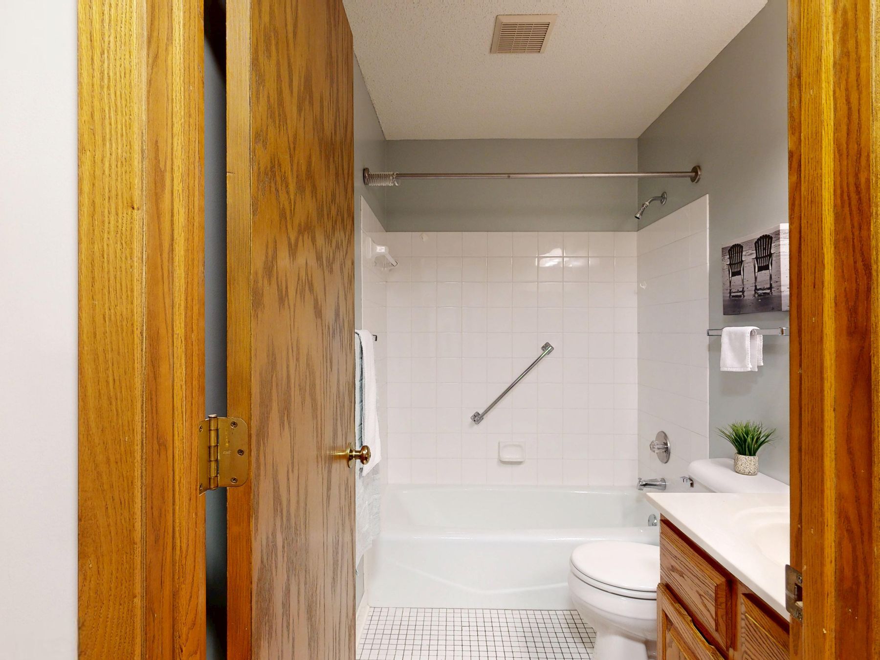 Bright modern bathroom with a warm wooden entry door, bathtub and pale finishes