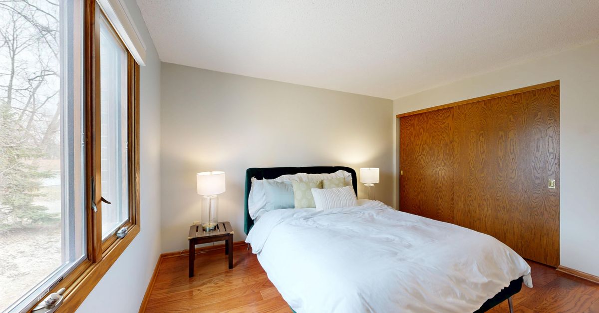 A clean and modern bedroom interior with a comfortable bed and wooden flooring.