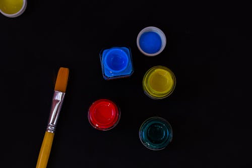 A Paint Brush And Acrylic Paint In Black Background