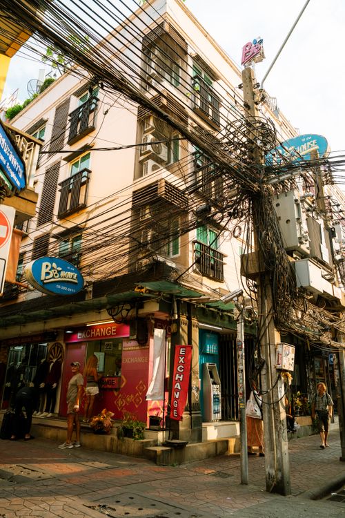 Free Vibrant city street scene featuring dense power lines and a currency exchange shop. Stock Photo
