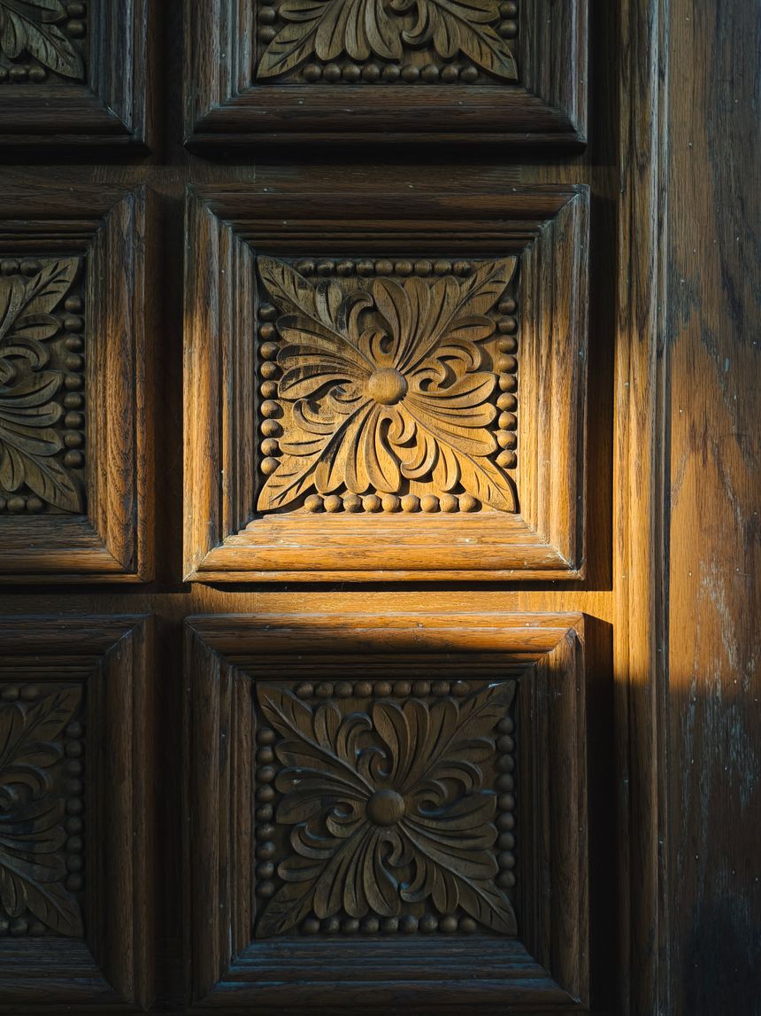 Late light raking across the carved panels of an old timber door