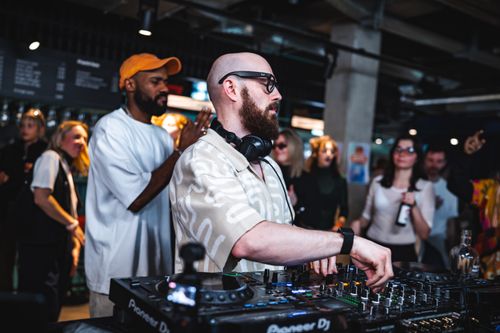 Free Energetic DJ performing at a bustling indoor party with engaged crowd. Stock Photo