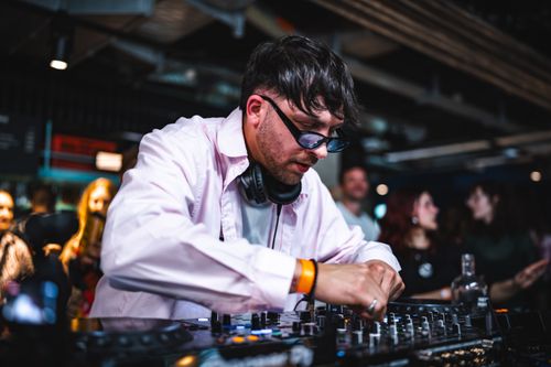 Free Vibrant shot of a DJ mixing live at a bustling indoor music event with an engaged audience. Stock Photo