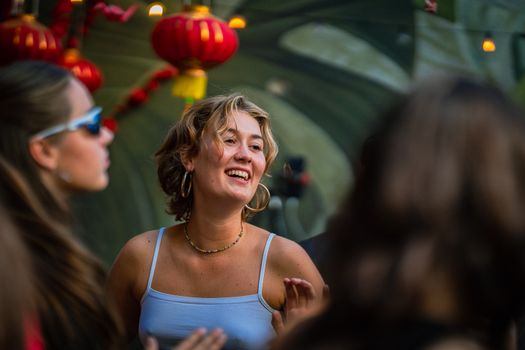 Young woman enjoying a lively outdoor festival with Chinese lanterns.