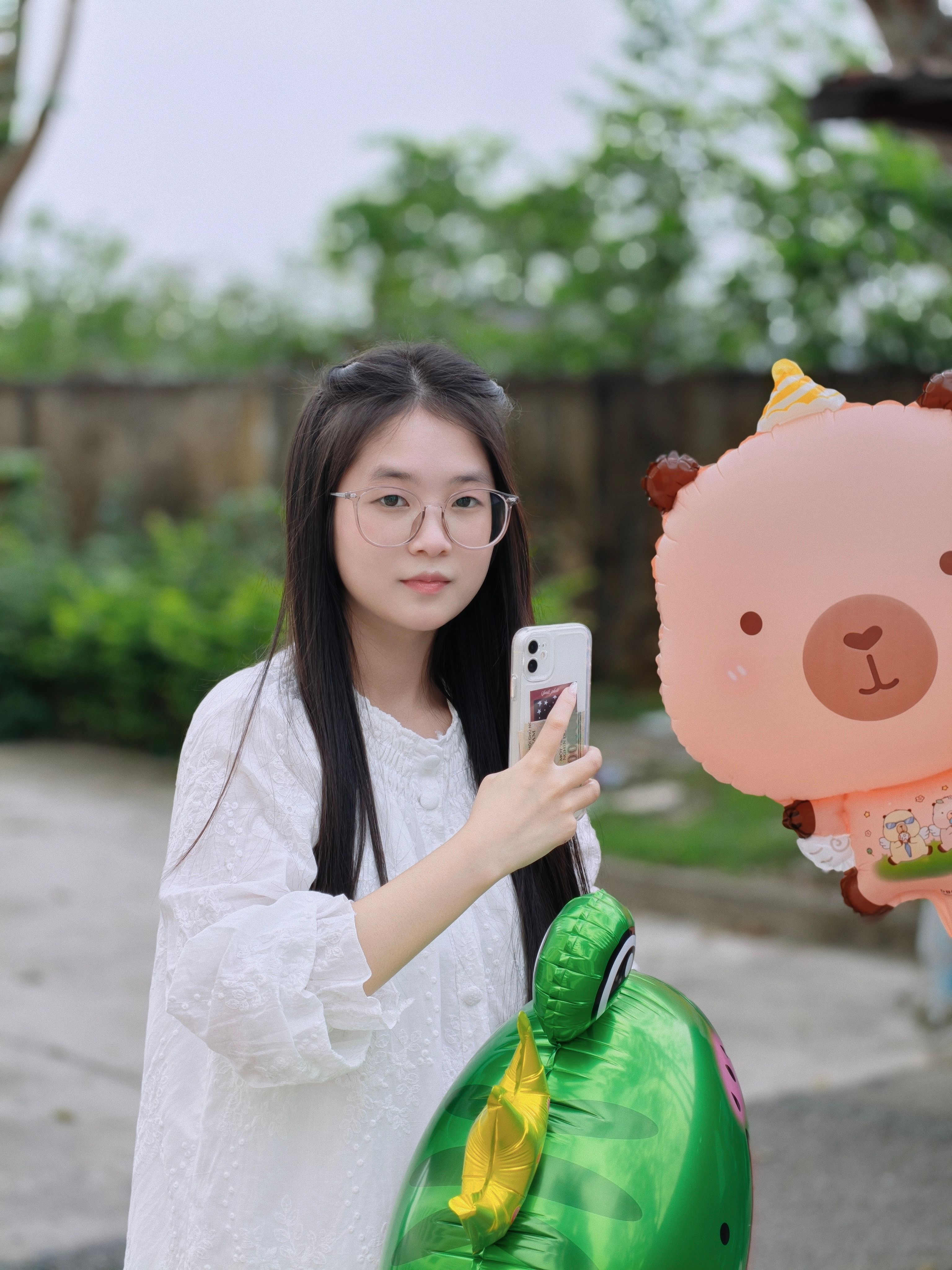 Woman Holding Balloons Outdoors with Smartphone