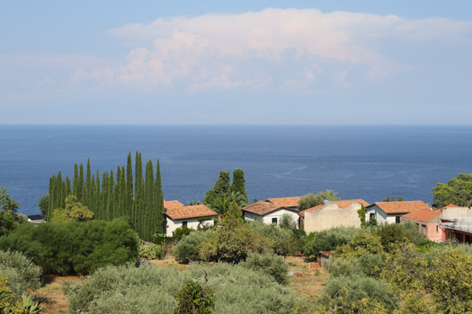 Idyllic seaside landscape in Taormina, Sicily, with red-roofed villas and lush greenery.